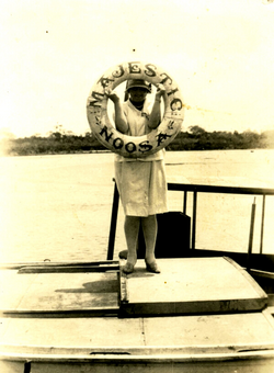 a lady holding a round majestic noosa signage